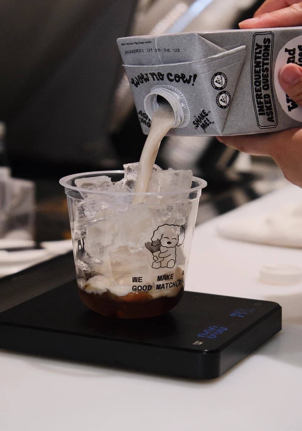 Milk poured from a Mitchie Matcha carton into a cup of ice on a scale