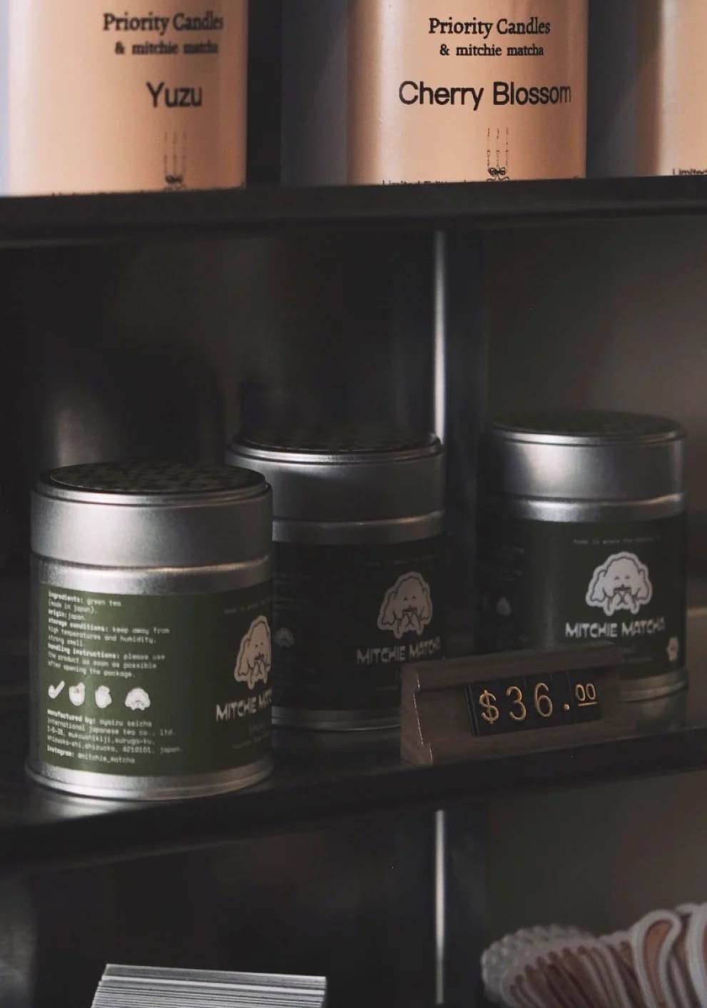 Mitchie Matcha tins on a dark retail shelf with a price tag